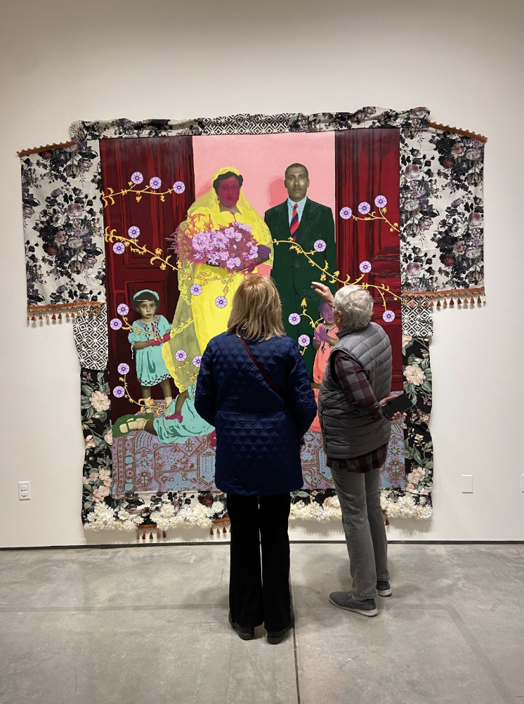 Opening night of a new exhibition “Before These Witnesses” gallery, attendees were engrossed in the art. Shown is an unltiled piece of a family in a wedding along with orange vines, flowers and various textiles. 